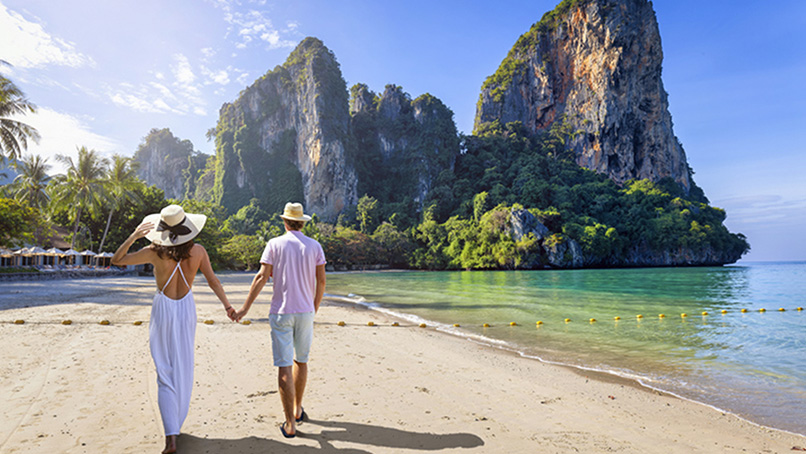 Couple walking a beach beneath limestone cliffs